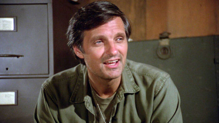 Actor in a classic TV show scene, smiling in a military jacket, capturing iconic series moments.