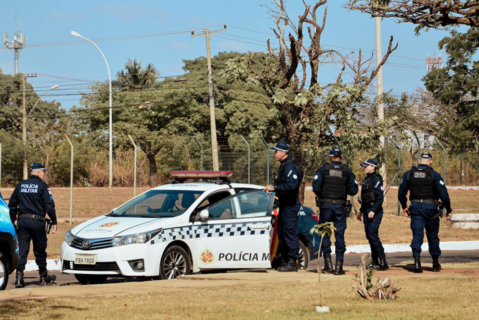 Police officers gathered near a patrol car in a park setting, responding to an incident involving a man and his wife. Police officers gathered near a patrol car in a park setting, responding to an incident involving a man and his wife.