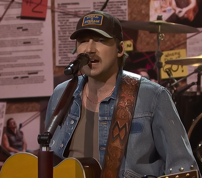 Musician in denim jacket performing on stage with a guitar and microphone. Musician in denim jacket performing on stage with a guitar and microphone.