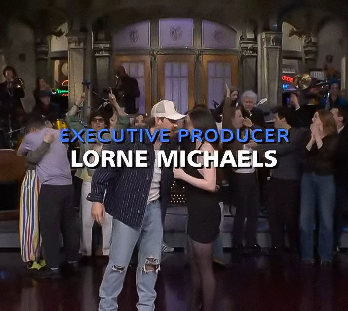 Morgan Wallen on SNL stage, wearing a white cap and denim, with background audience and credits displayed. Morgan Wallen on SNL stage, wearing a white cap and denim, with background audience and credits displayed.