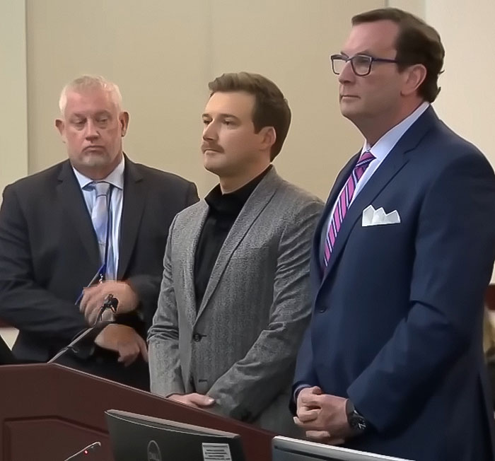 Three men standing together in a formal setting, involved in a discussion about a petulant move. Three men standing together in a formal setting, involved in a discussion about a petulant move.