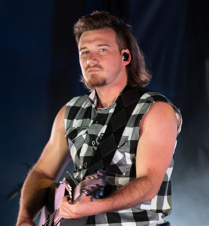 Musician in a sleeveless plaid shirt playing a guitar, related to a "Petulant Move" incident on 'SNL' stage. Musician in a sleeveless plaid shirt playing a guitar, related to a "Petulant Move" incident on 'SNL' stage.