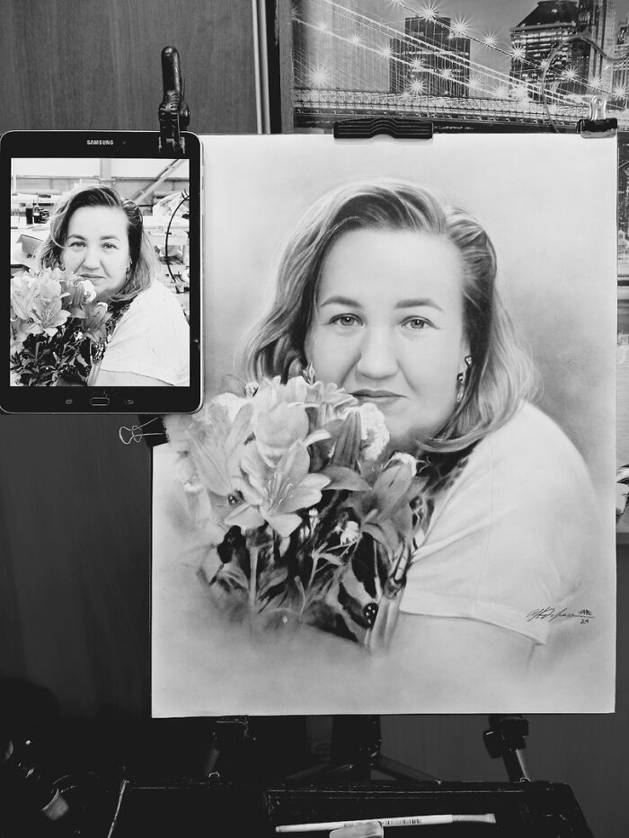 Hyper-realistic pencil portrait of a woman holding flowers, next to a tablet displaying the reference photo.