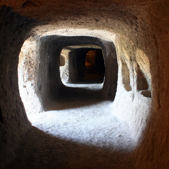 Underground tunnel in an eerie city with stone walls and dim lighting.