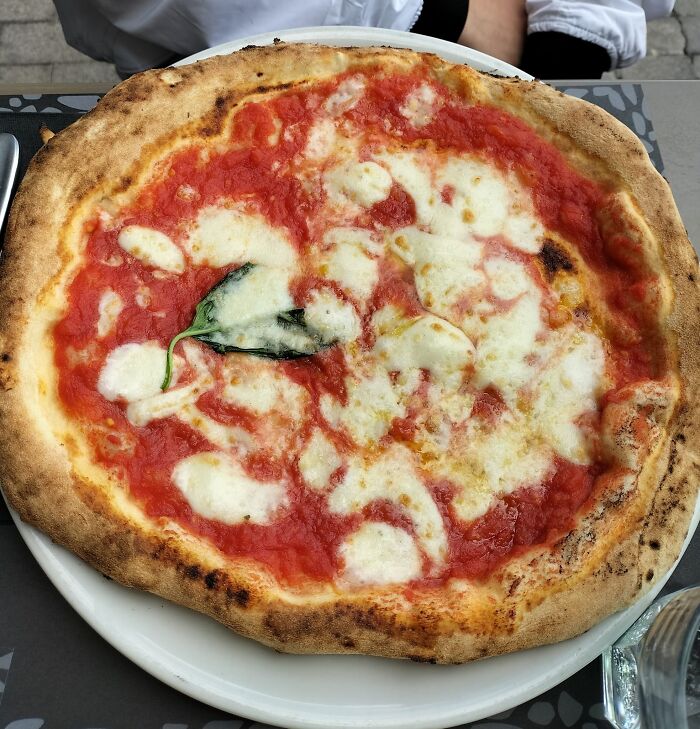 Top dish from Italy, Margherita pizza with fresh basil and melted mozzarella on a crispy crust.