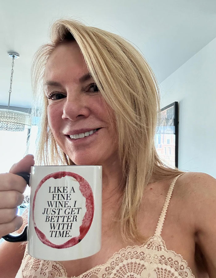 Blonde woman holds a mug with a quote, showing a visibly altered facial appearance, sparking Photoshop controversy. Blonde woman holds a mug with a quote, showing a visibly altered facial appearance, sparking Photoshop controversy.