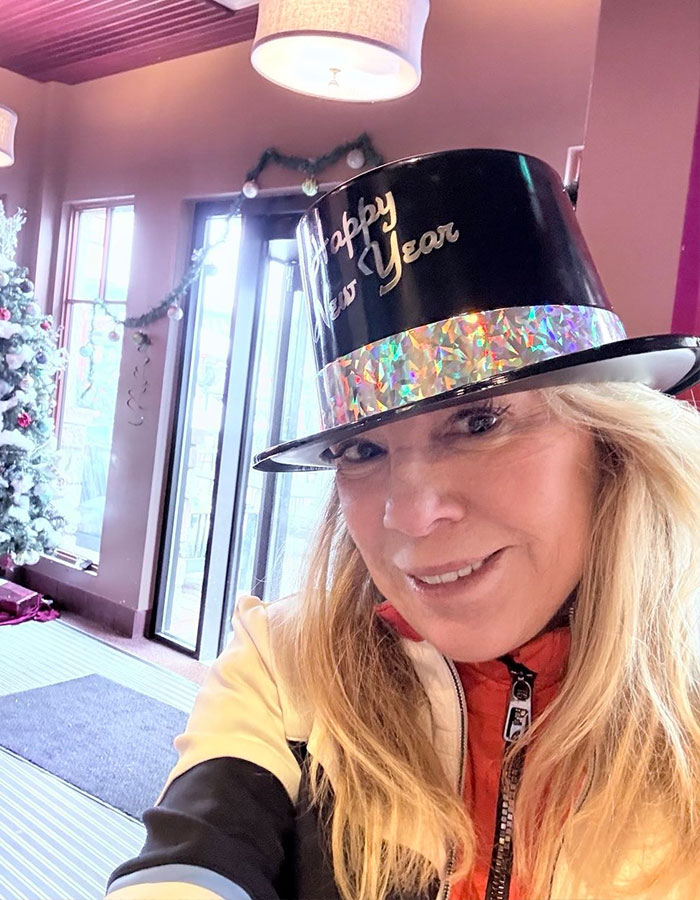 Woman in a New Year's hat smiling indoors, with festive decor in the background. Woman in a New Year's hat smiling indoors, with festive decor in the background.