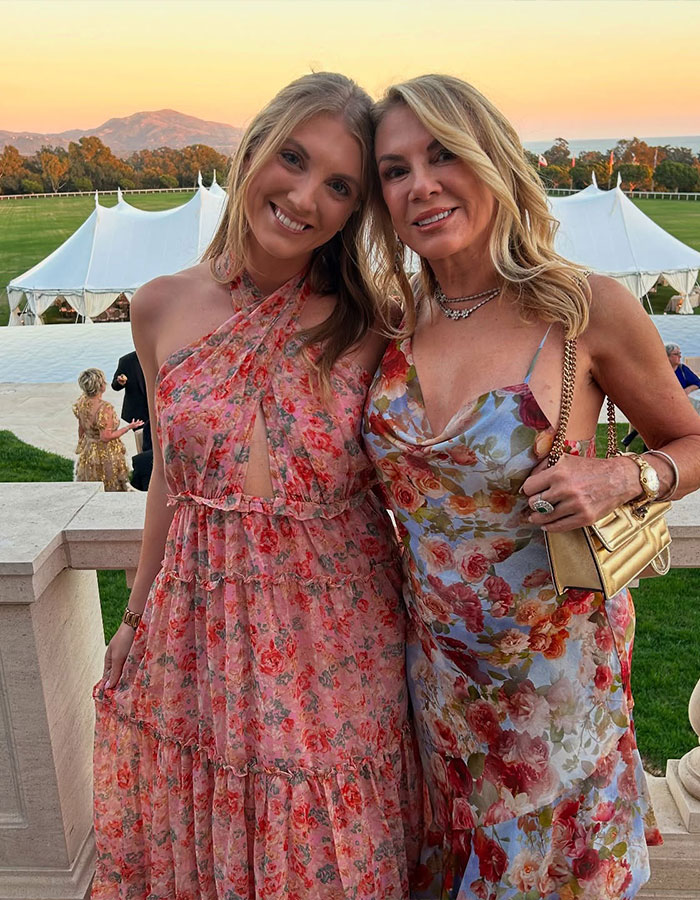 Two women in floral dresses pose at sunset, surrounded by elegant outdoor decor, featuring obvious photoshop use. Two women in floral dresses pose at sunset, surrounded by elegant outdoor decor, featuring obvious photoshop use.