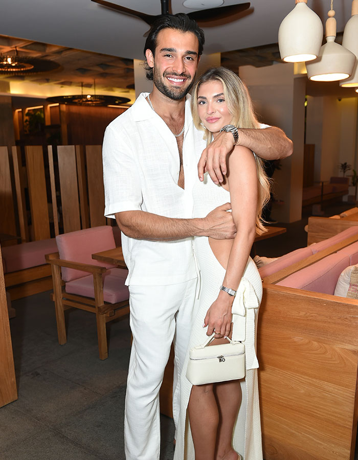 I don't know who these people are, but they are smiling and embracing in a well-lit room, wearing stylish white outfits. I don't know who these people are, but they are smiling and embracing in a well-lit room, wearing stylish white outfits.