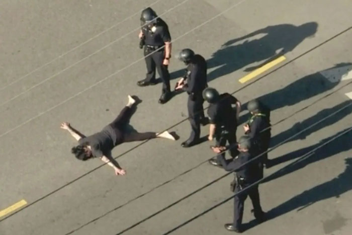 Police in tactical gear surround individual on the ground, aerial view, related to Weezer bassist incident. Police in tactical gear surround individual on the ground, aerial view, related to Weezer bassist incident.