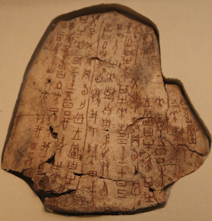 Ancient written text on a fractured stone tablet with characters, showcasing one of the world's oldest surviving texts.