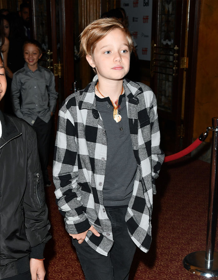 Shiloh Jolie-Pitt in checkered shirt at an event, showcasing transformation into a viral dancer. Shiloh Jolie-Pitt in checkered shirt at an event, showcasing transformation into a viral dancer.