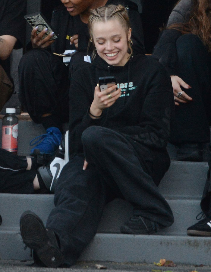 Young dancer in casual attire, sitting and smiling at a phone, showcasing transformation and style. Young dancer in casual attire, sitting and smiling at a phone, showcasing transformation and style.