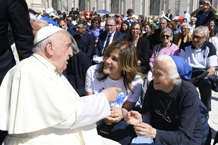 Pope Francis talking to seated nun and woman in crowd, engaging warmly in a public gathering. Pope Francis talking to seated nun and woman in crowd, engaging warmly in a public gathering.