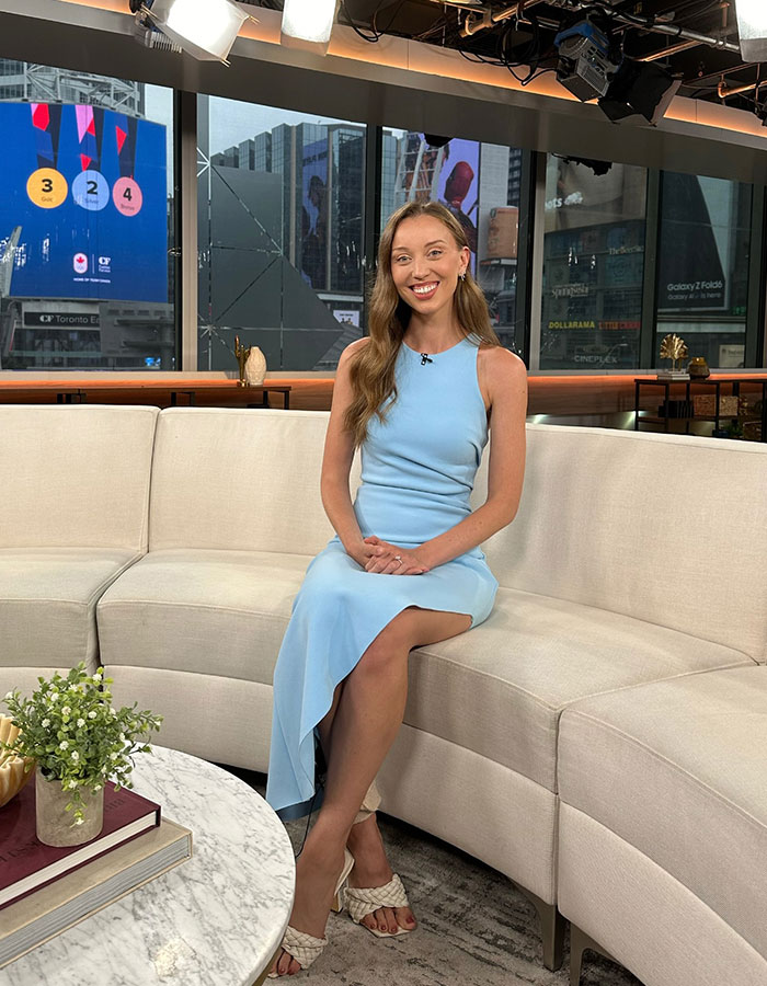 TV reporter in a blue dress sitting on a couch in a studio set. TV reporter in a blue dress sitting on a couch in a studio set.