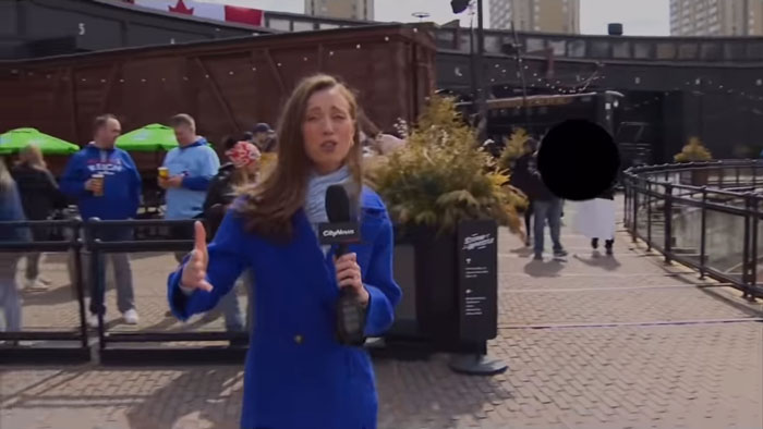 TV reporter in blue coat holding a microphone in an outdoor setting, surrounded by people, discussing misogynistic comments. TV reporter in blue coat holding a microphone in an outdoor setting, surrounded by people, discussing misogynistic comments.