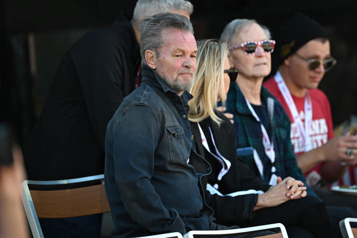 Man in denim jacket sitting with others, sharing a solemn moment, related to Teddi Mellencamp's cancer battle. Man in denim jacket sitting with others, sharing a solemn moment, related to Teddi Mellencamp's cancer battle.