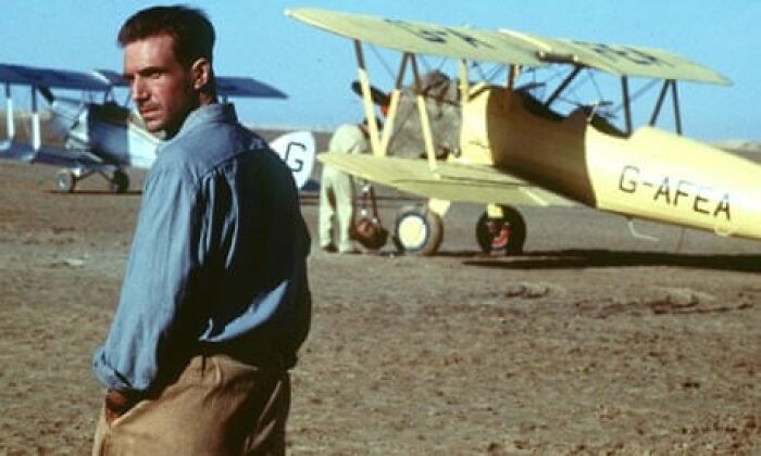 Man standing in front of vintage airplane, set in a desert scene from a movie known to cause tears.