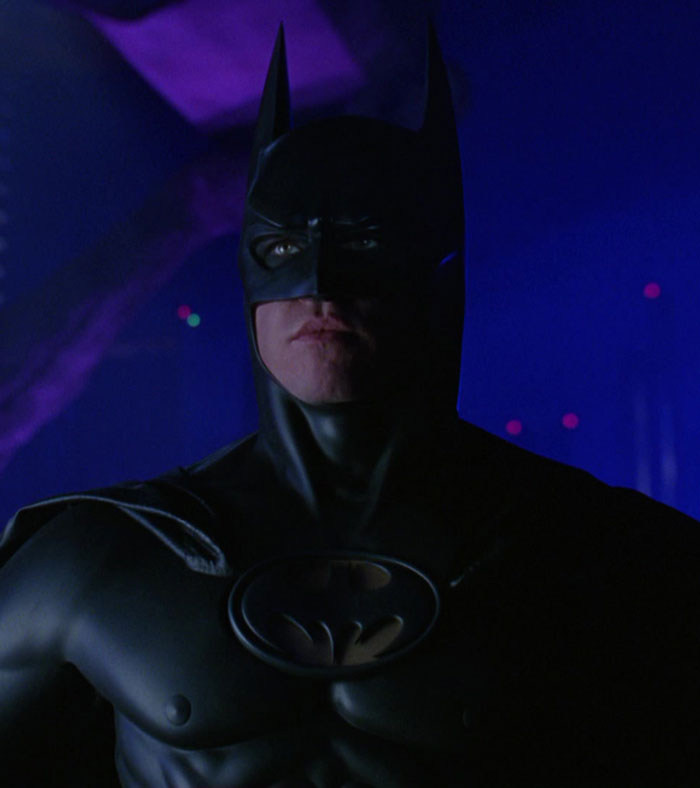 Batman portrayed in a dark setting, wearing iconic suit, associated with Val Kilmer's legacy. Batman portrayed in a dark setting, wearing iconic suit, associated with Val Kilmer's legacy.