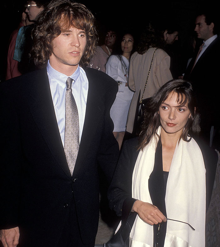 A man in a suit and a woman with a scarf at a formal event, amid a lively Hollywood gathering. A man in a suit and a woman with a scarf at a formal event, amid a lively Hollywood gathering.