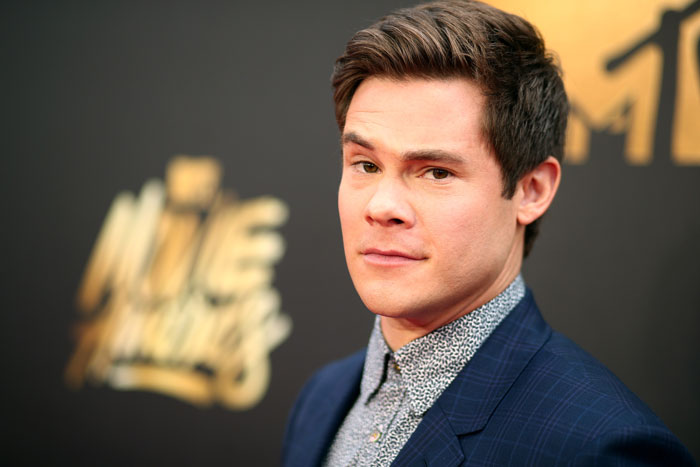 Actor from 'Pitch Perfect' on a red carpet, wearing a dark blue suit and patterned shirt. Actor from 'Pitch Perfect' on a red carpet, wearing a dark blue suit and patterned shirt.