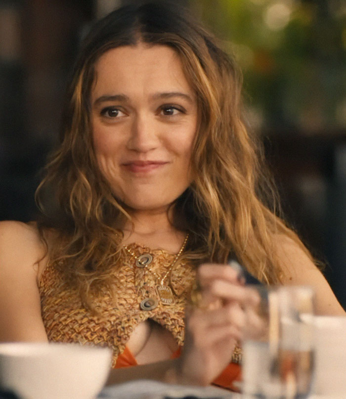 Woman smiling with long hair, wearing a textured top, sitting at a table. Woman smiling with long hair, wearing a textured top, sitting at a table.