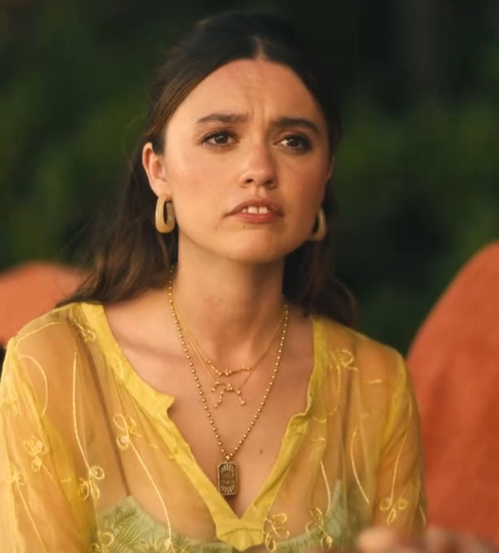 Woman in a yellow blouse with layered necklaces, reacting emotionally, outdoors. Woman in a yellow blouse with layered necklaces, reacting emotionally, outdoors.