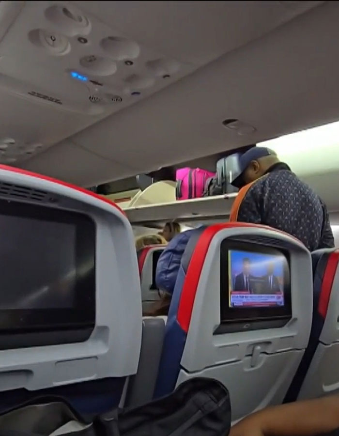 Passengers inside Delta airplane, seated and standing, during a tarmac delay caused by storms. Passengers inside Delta airplane, seated and standing, during a tarmac delay caused by storms.
