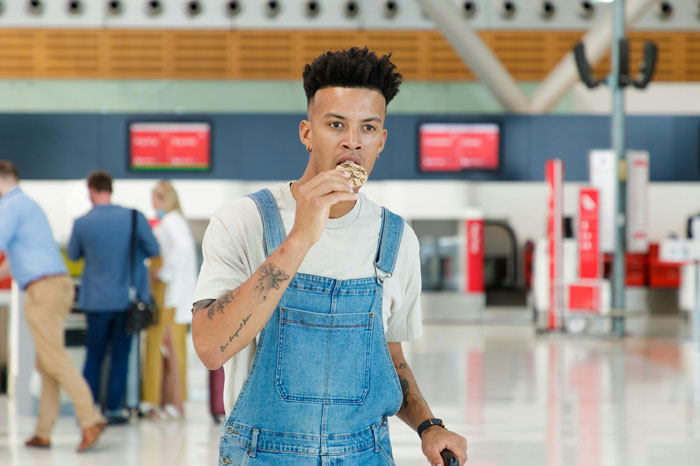 Person eating a snack at the airport, despite nutritionist advice to avoid certain foods and drinks like alcohol and beans. Person eating a snack at the airport, despite nutritionist advice to avoid certain foods and drinks like alcohol and beans.