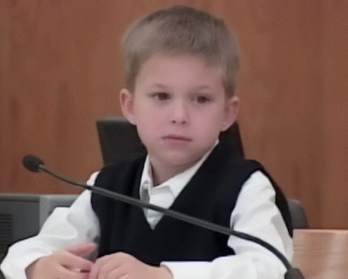 Young boy in a courtroom setting, wearing a vest and white shirt, related to the life sentence story. Young boy in a courtroom setting, wearing a vest and white shirt, related to the life sentence story.