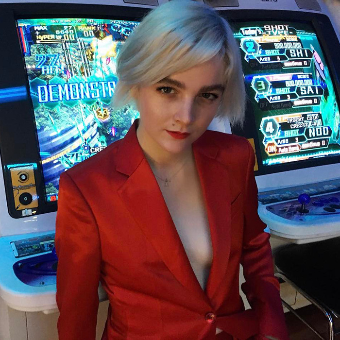 Person in a red suit stands confidently in front of a gaming machine. Person in a red suit stands confidently in front of a gaming machine.