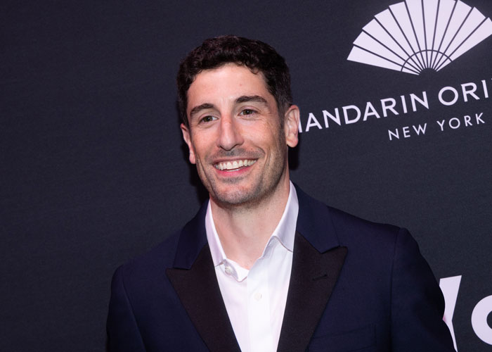Actor in NYC event showcasing significant weight loss, smiling in a suit against a branded backdrop. Actor in NYC event showcasing significant weight loss, smiling in a suit against a branded backdrop.