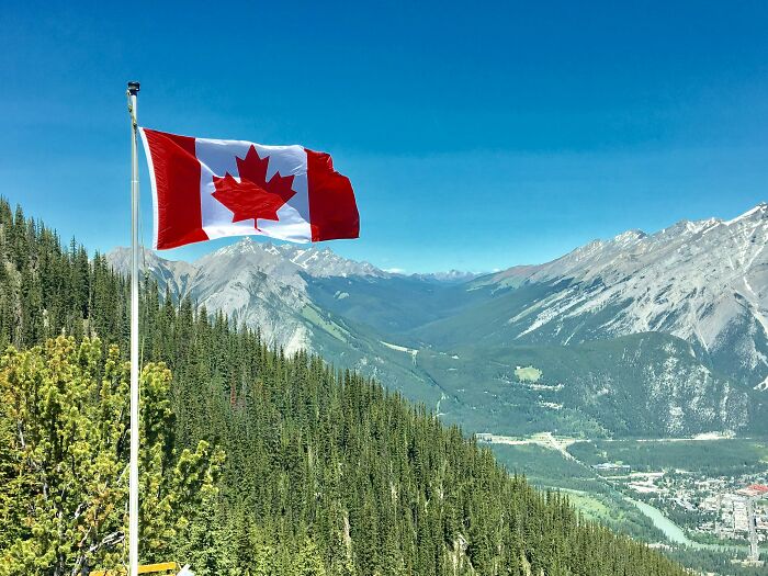 Canadian landscape with a prominent flag, capturing ways to identify an American tourist among the scenic mountains.