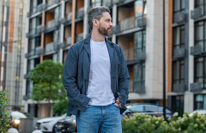 Man in casual attire standing on city street, embodying typical tourist traits.