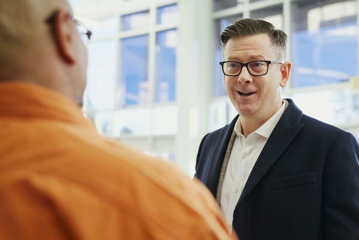 A man in glasses conversing indoors, capturing an American tourist vibe.