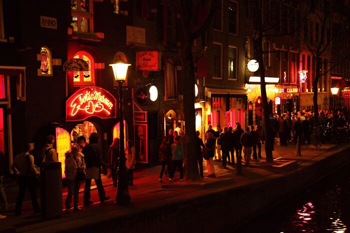Crowds of tourists visiting a brightly lit nightlife area at night.