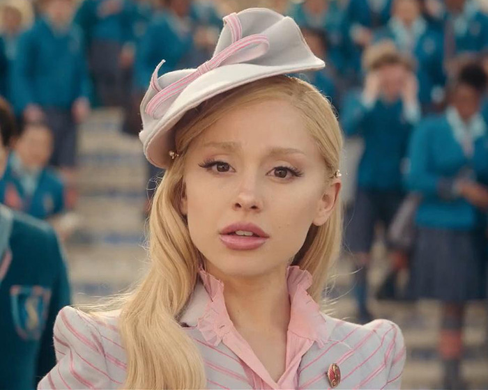 Ariana Grande with new hairstyle and tattoos, standing in a crowd, wearing a stylish hat. Ariana Grande with new hairstyle and tattoos, standing in a crowd, wearing a stylish hat.