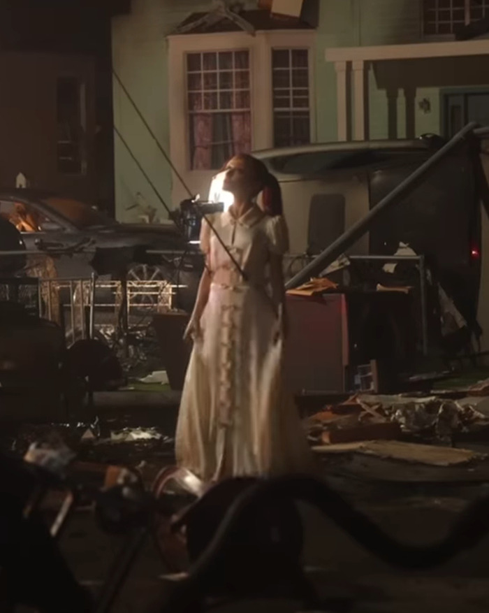 A woman in a flowing dress stands amidst a cluttered outdoor scene, showcasing tattoos and a new hair transformation. A woman in a flowing dress stands amidst a cluttered outdoor scene, showcasing tattoos and a new hair transformation.