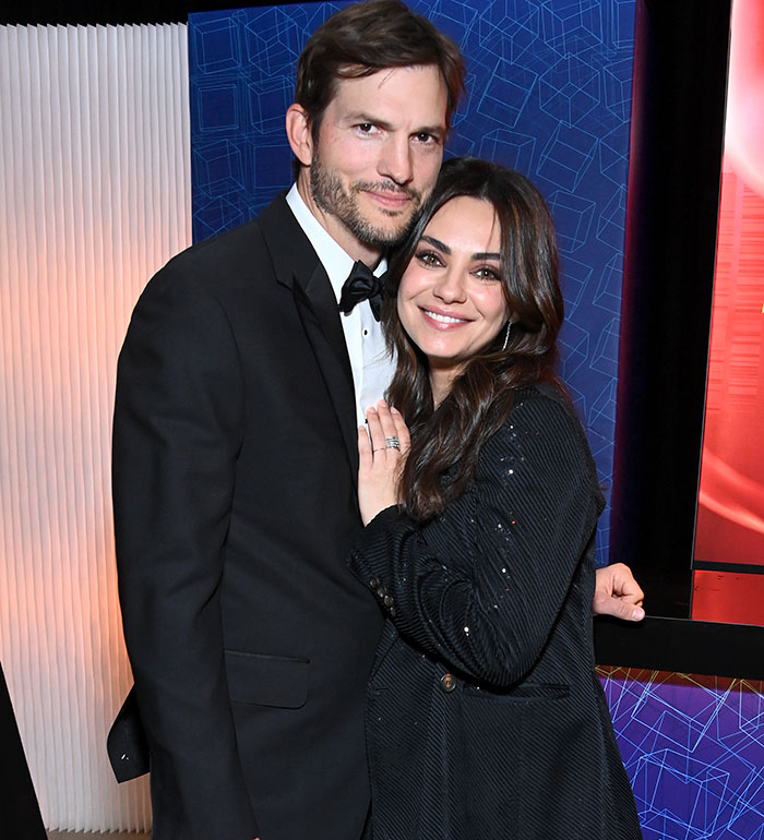 A man in a tuxedo and a woman in a black outfit pose closely together at a formal event. A man in a tuxedo and a woman in a black outfit pose closely together at a formal event.