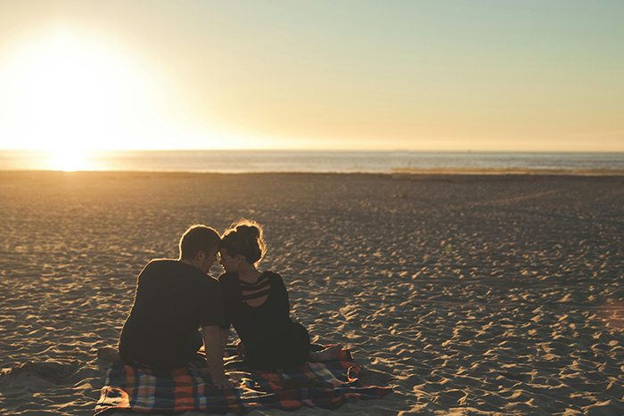 Couple sitting on a beach at sunset, illustrating themes of relationships and marriage discussions. Couple sitting on a beach at sunset, illustrating themes of relationships and marriage discussions.