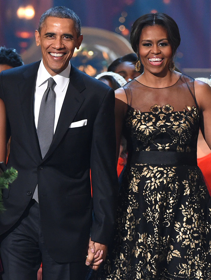A couple holding hands, both smiling, in formal attire, attending a public event. A couple holding hands, both smiling, in formal attire, attending a public event.