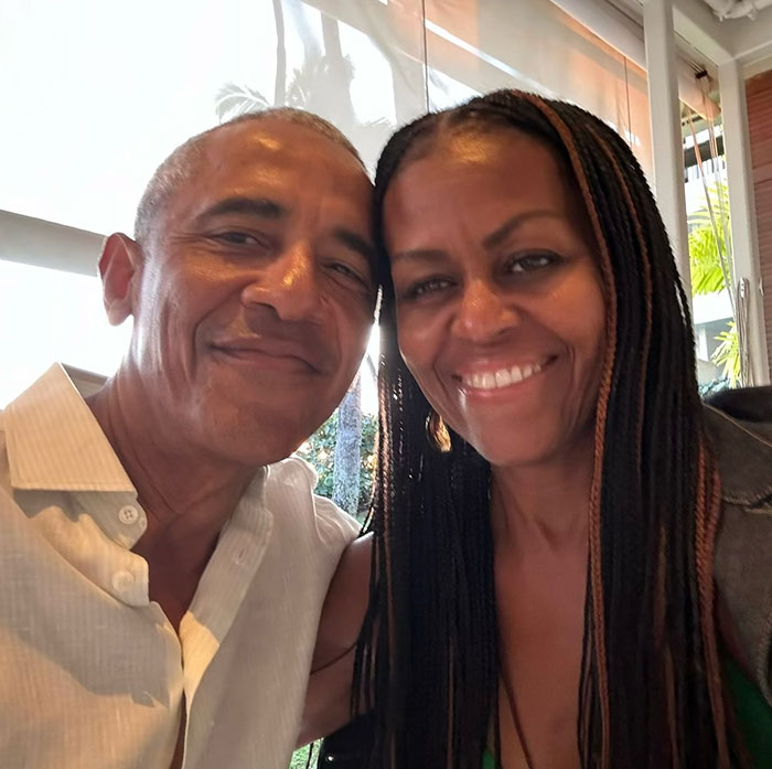 Michelle Obama smiling beside a man, both in a relaxed setting, addressing divorce rumors. Michelle Obama smiling beside a man, both in a relaxed setting, addressing divorce rumors.