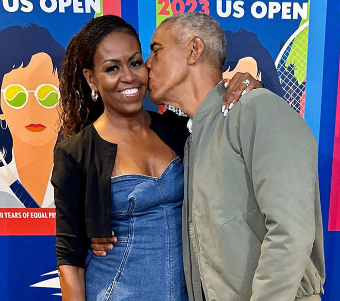 Michelle Obama smiling at US Open amidst divorce rumors, receiving a kiss on the cheek. Michelle Obama smiling at US Open amidst divorce rumors, receiving a kiss on the cheek.
