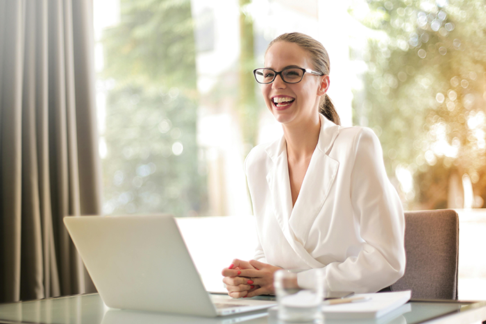 Smiling woman in glasses and white blazer using a laptop, representing an upset ex-girlfriend in a marriage scenario. Smiling woman in glasses and white blazer using a laptop, representing an upset ex-girlfriend in a marriage scenario.