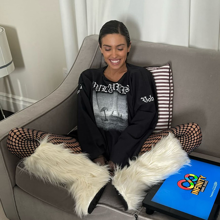 Woman seated on sofa in a relaxed pose with furry boots, smiling, phone nearby. Woman seated on sofa in a relaxed pose with furry boots, smiling, phone nearby.