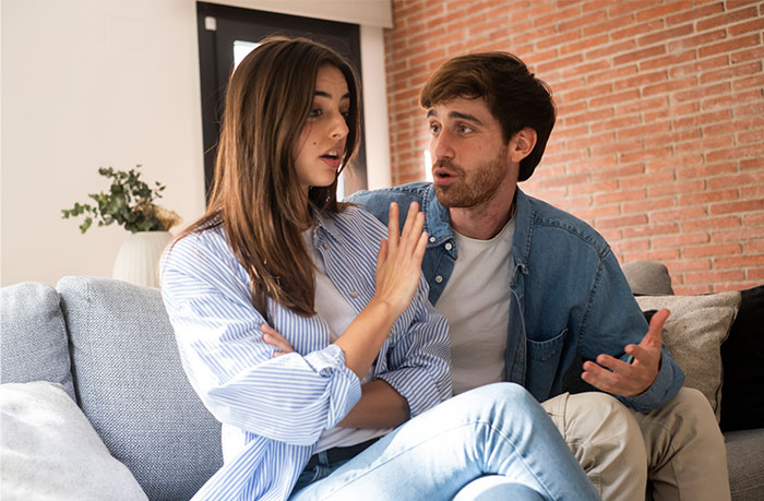 Man surprised talking to woman on a sofa, expressing disbelief about a marriage-related issue. Man surprised talking to woman on a sofa, expressing disbelief about a marriage-related issue.
