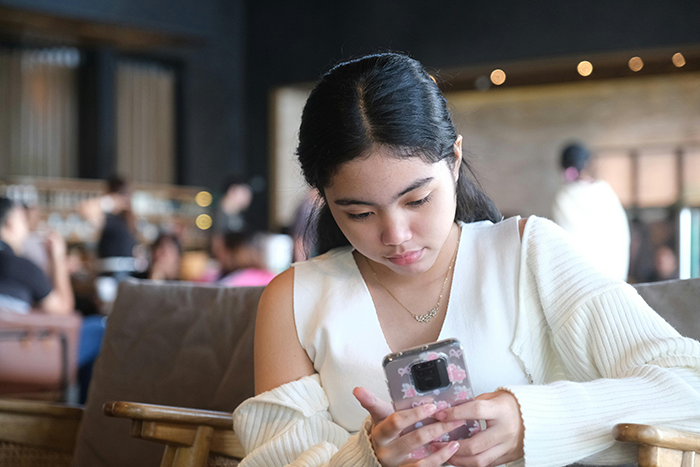 Young woman in a cafe using a smartphone, surrounded by a cozy atmosphere. Young woman in a cafe using a smartphone, surrounded by a cozy atmosphere.
