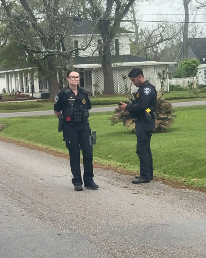 Police officers standing in a residential street, with a house in the background. Police officers standing in a residential street, with a house in the background.
