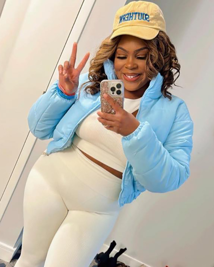 Woman sues restaurant, poses in mirror wearing a blue jacket and beige outfit, smiling with a peace sign. Woman sues restaurant, poses in mirror wearing a blue jacket and beige outfit, smiling with a peace sign.