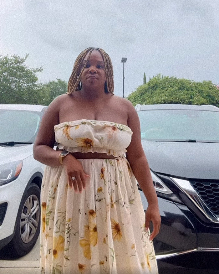 Woman in floral dress outside, related to lawsuit against restaurant over outfit being considered too revealing. Woman in floral dress outside, related to lawsuit against restaurant over outfit being considered too revealing.